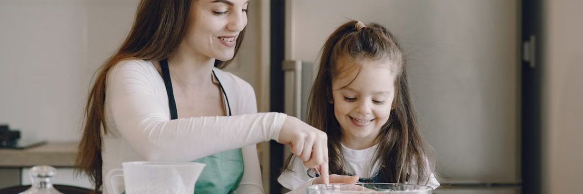 A mother and daughter share a bonding moment while baking together in a kitchen.