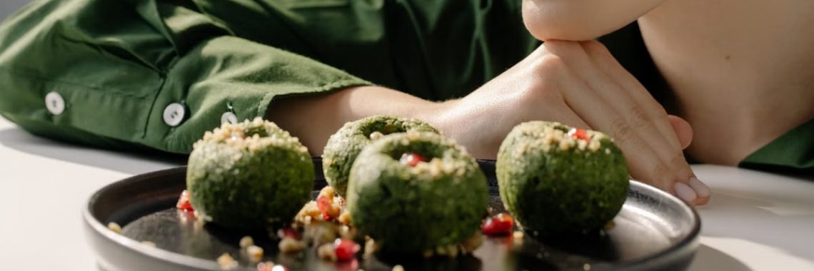 Close-up of spinach pkhali, a Georgian vegan dish, with a woman in green observing.